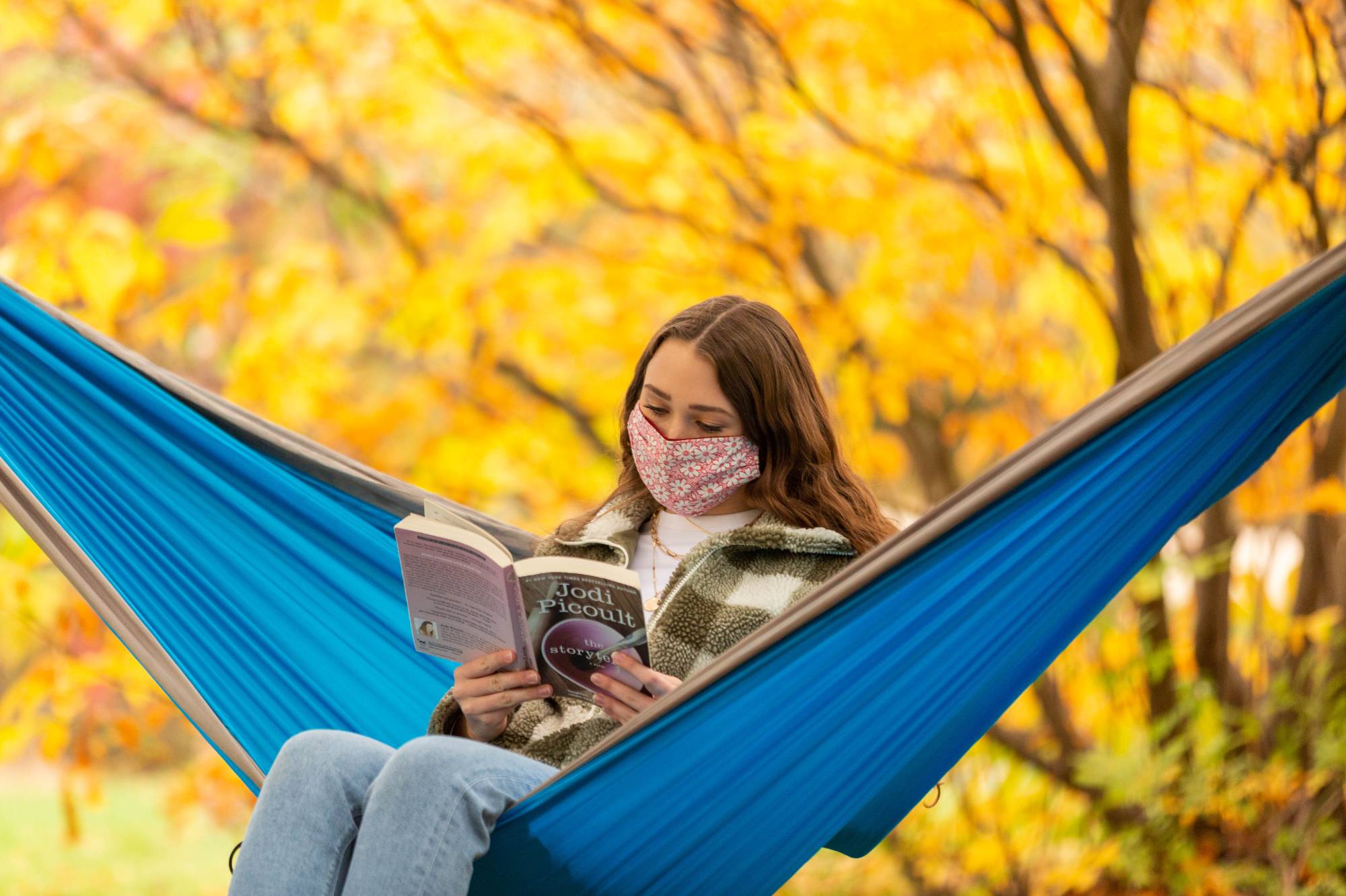 Student reading a book in a hammock.